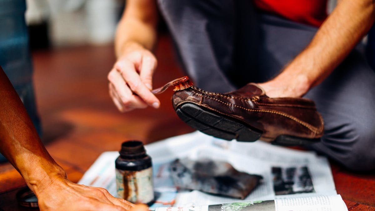 Close-up of hands skillfully polishing a leather shoe, showcasing craftsmanship and care.