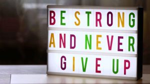 Motivational lightbox sign displaying 'Be Strong and Never Give Up.'